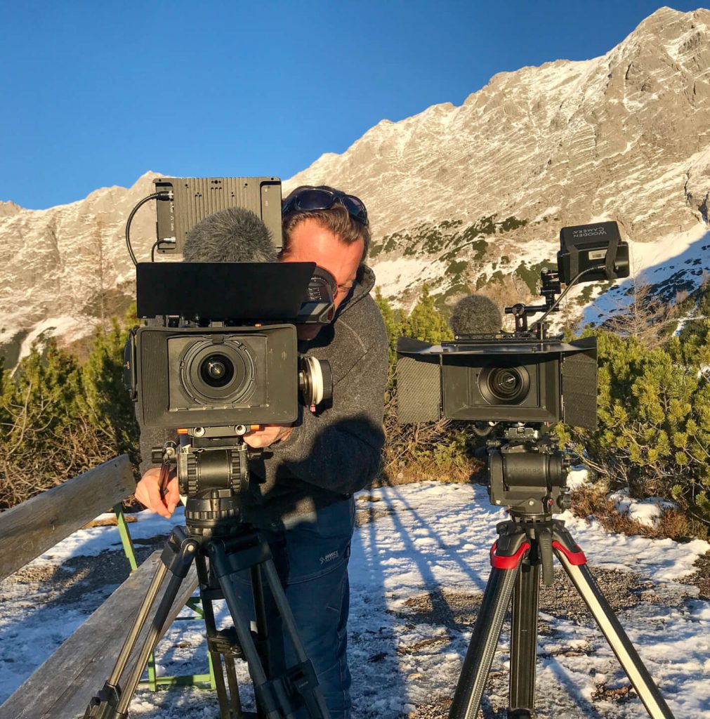 Kameramann filmt mit zwei Videokameras im verschneiten Gebirge für professionelle Filmproduktion