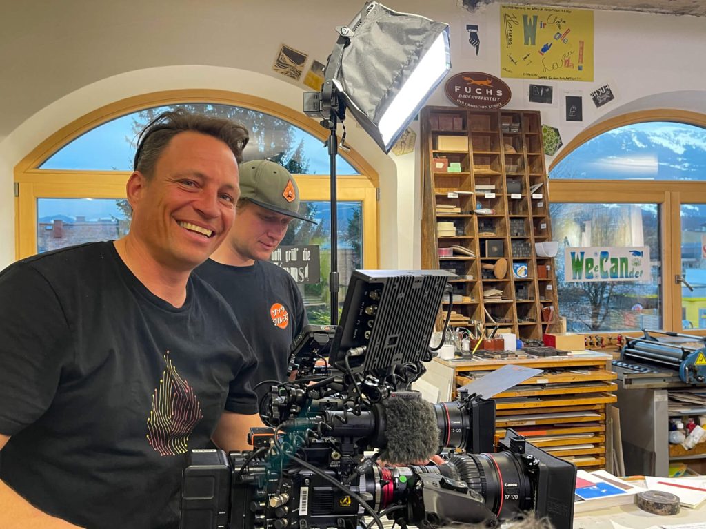 Zwei Männer mit Kamera-Equipment bei Videoproduktion, helles Studio, Luftaufnahmen, Filmproduktion