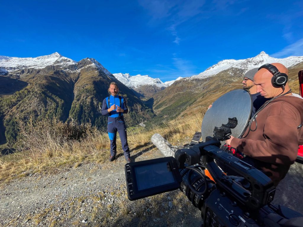 Videodreh mit Kamera und Toncrew vor Alpenpanorama für professionelle Luftaufnahmen